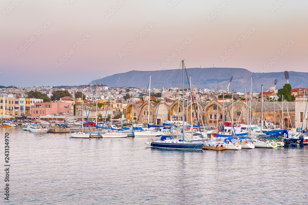 Travel Concepts. Picturesque Image of Old Venetian Harbour of Chania with line of Fisihing Boats and Yachts in the Foregound Against Clear Sky in Crete