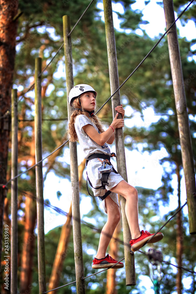 route in a rope park - a young girl on the obstacles