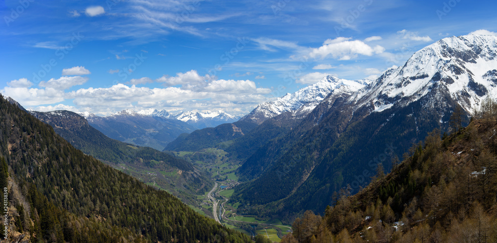 Beautiful top view panorama of high snow-covered mountains and valley with road and village in Switzerland at spring