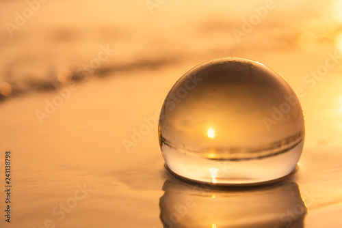 Crystal ball on the beach with sea waves at morning sunrise.Thailand.