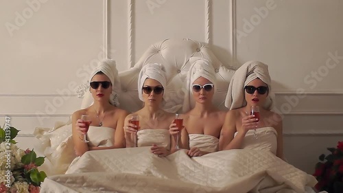 four girls in towels lie in bed and stare fixedly at the camera. girlfriends spend time together. girls at a bachelorette party in the spa