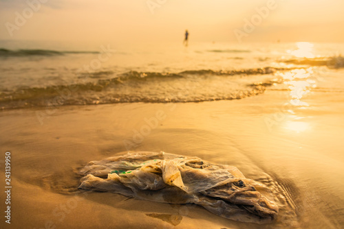 Plastic bag on the beach with sea waves at morning sunrise.Thailand.