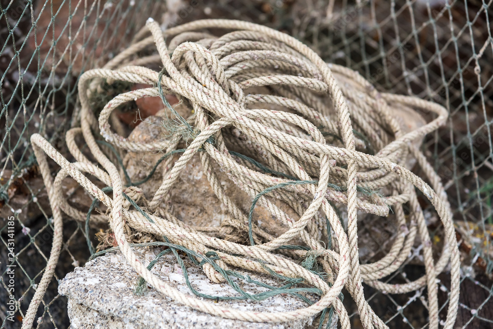 Gray sea ropes lie in a heap in fishing port.Thailand.