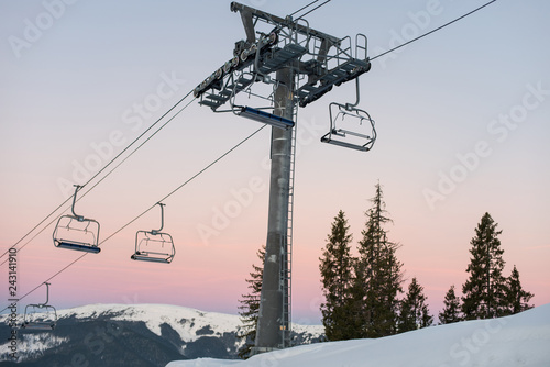 Ski lift chairs on winter resort against a amazing sky at sunset