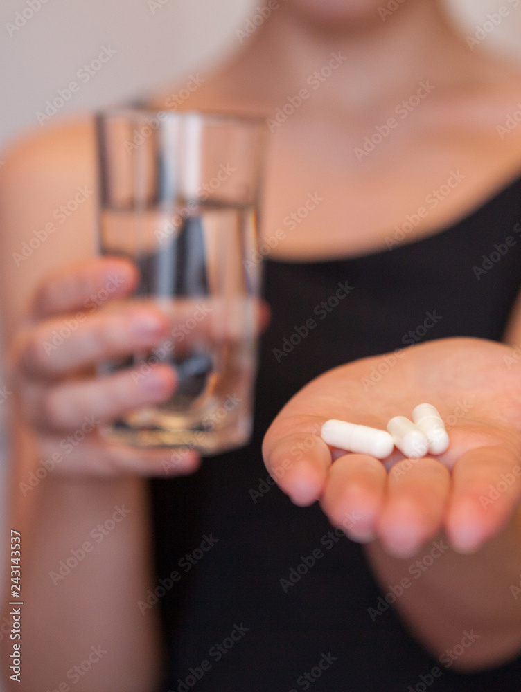 Fototapeta premium Close Up Of Girl holding Pill and glass of water.With Paracetamol.Nutritional Supplements.Sport,Diet Concept.Capsules Vitamin And Dietary Supplements