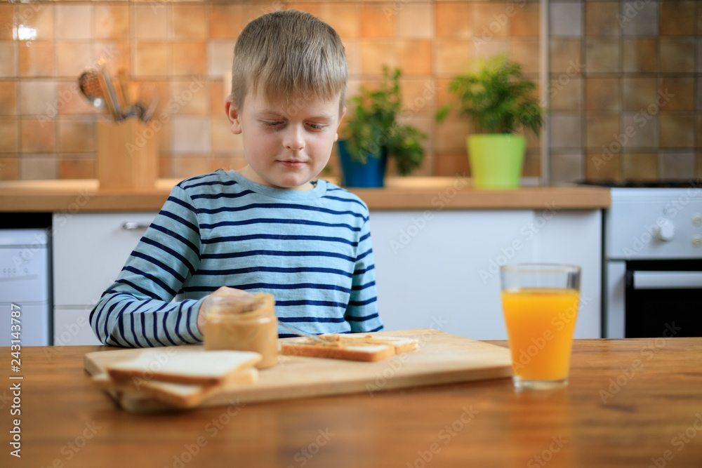 Boy making a sandwich with peanut butter on the kitchen Boy making a sandwich with peanut butter on the kitchen