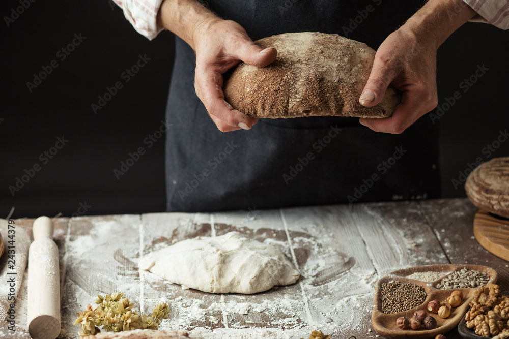 Φωτογραφία Hands of undentified baker man in cooking wear, holding homemade sourdough bread