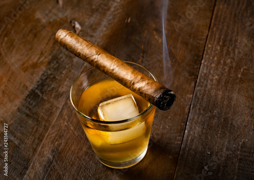 Cigar resting on whiskey glass