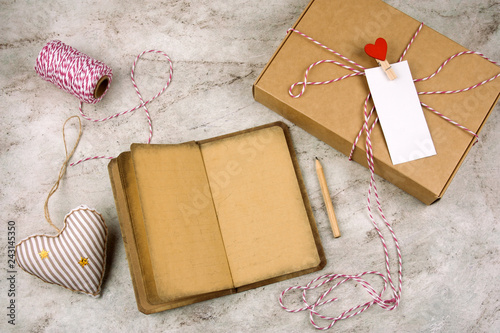 top view open noteboock with old vintage paper, pencil, gift box with blank white label, hearts on a marble background photo