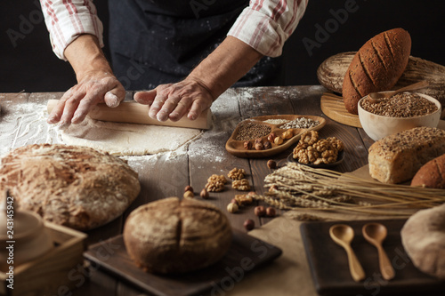 Different kinds of fresh bread, focaccia, typical Italian bread with crispy and very tasty crust and male hands rolling out dough for Italian pizza. Healthy eating and traditional bakery concept.