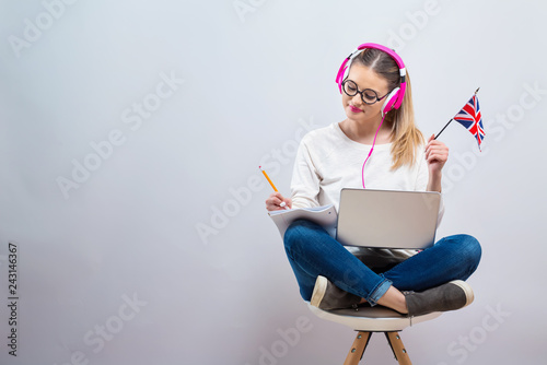 Young woman with UK flag using a laptop computer on a gray background