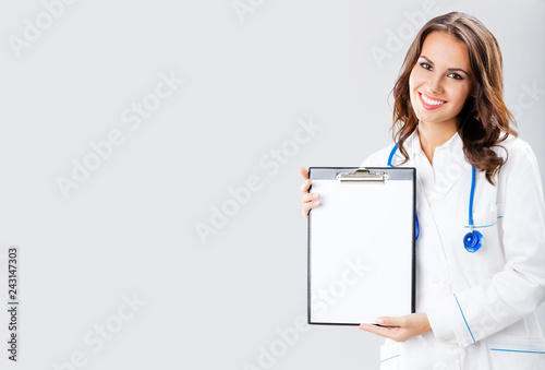 Female doctor showing blank clipboard, on grey