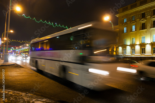Motion blurred white bus on the avenue in the evening in the winter.