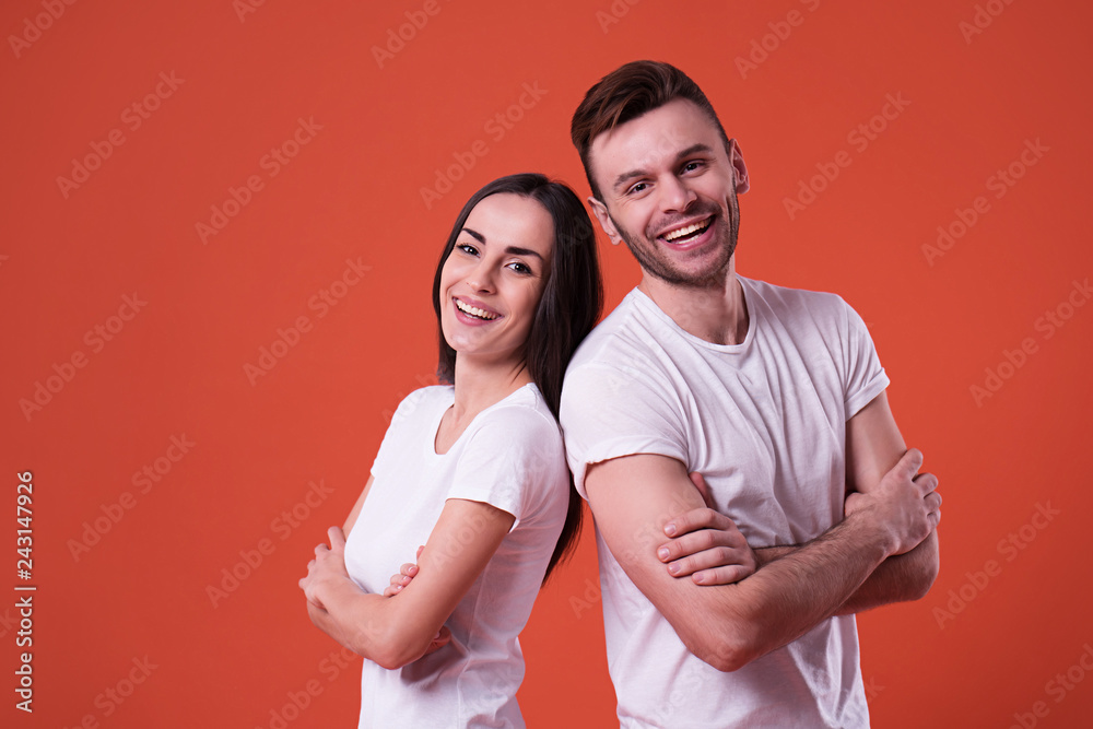 Happy and excited couple are posing in white t-shirts on orange background Happy and excited couple are posing in white t-shirts on orange background