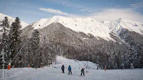Happy group of skiers having fun sitting in snowdrift with snowboards and tossing snow