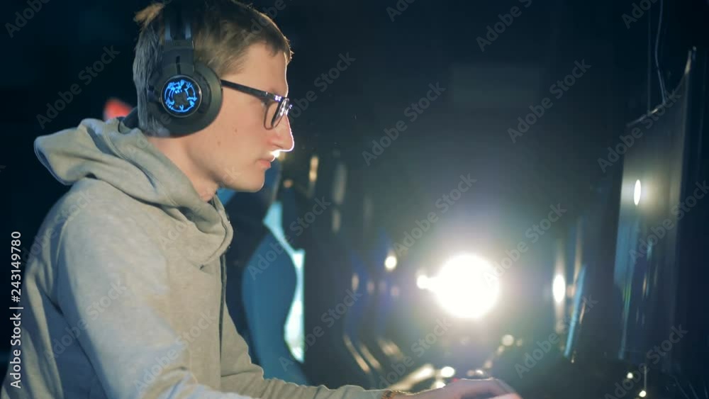 Young man puts on earphones and starts playing on the computer Young man puts on earphones and starts playing on the computer