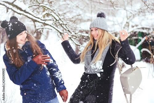funny and happy two beautiful girlfriends play in the snow in winter, a lot of snow and winter clothes. blonde and brunette emotions