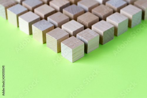 Wood cubes or blocks arranged in geometrical pattern on green background