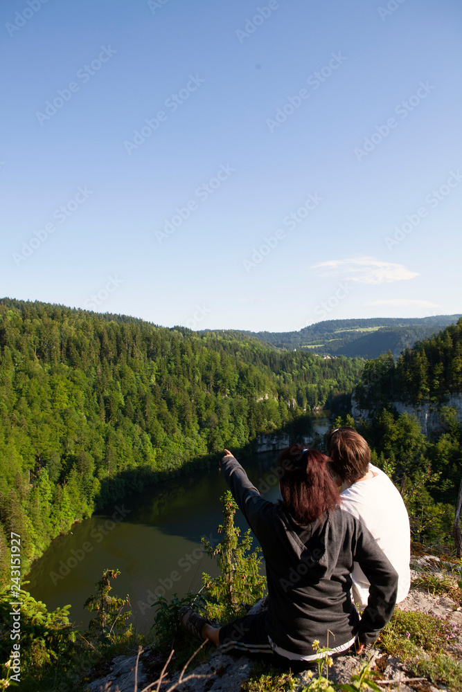 Couple enjoying breathtaking landscape from top of a cliff Couple enjoying breathtaking landscape from top of a cliff