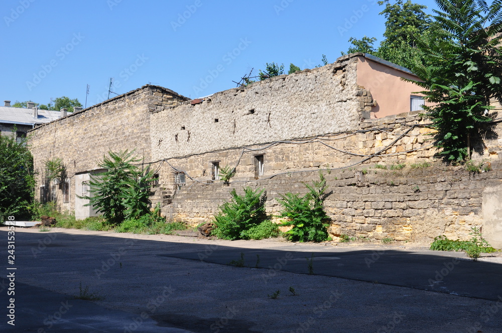 Naklejka premium Old destroyed stone house on the yard with trees around. Poverty and misery, South, summer 