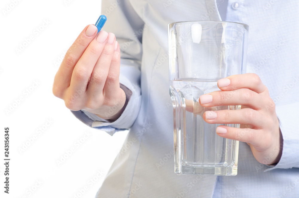 Blue capsule pill and glass of water medicine in woman hand on white background, pharmacy concept Blue capsule pill and glass of water medicine in woman hand on white background, pharmacy concept