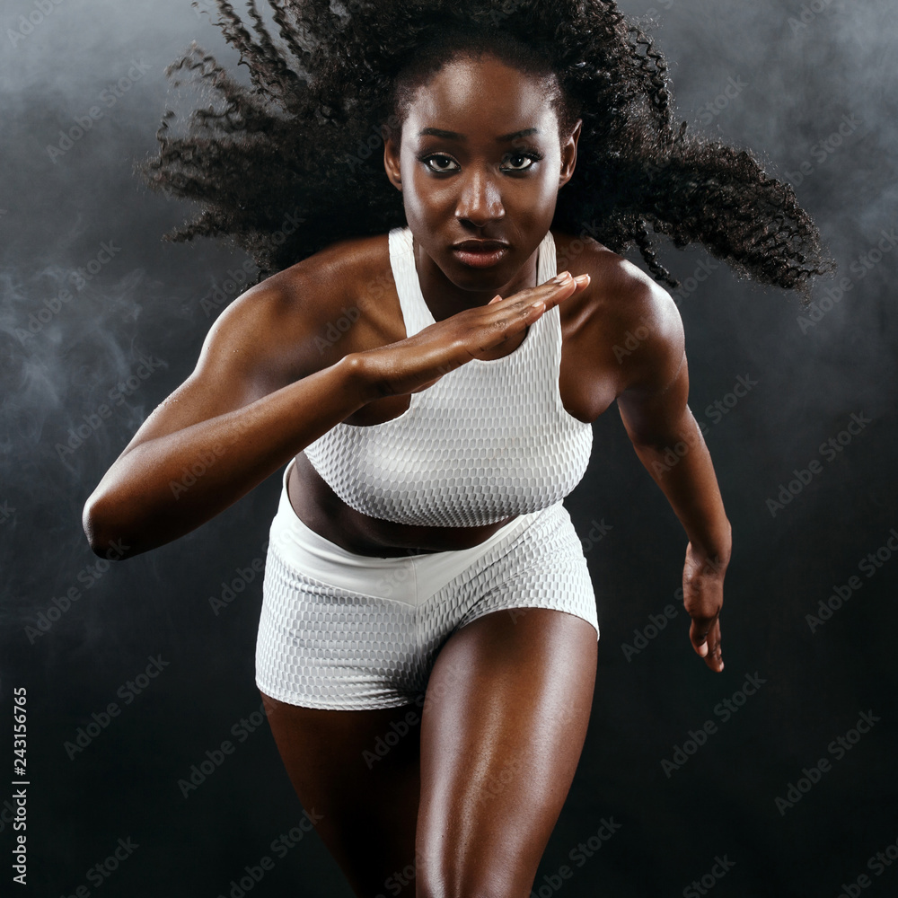 Strong athletic black skin woman sprinter, running on background