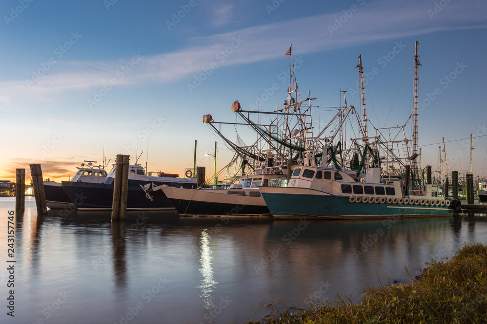 Large shrimping boats waiting to go to work as sun sets in distance Large shrimping boats waiting to go to work as sun sets in distance