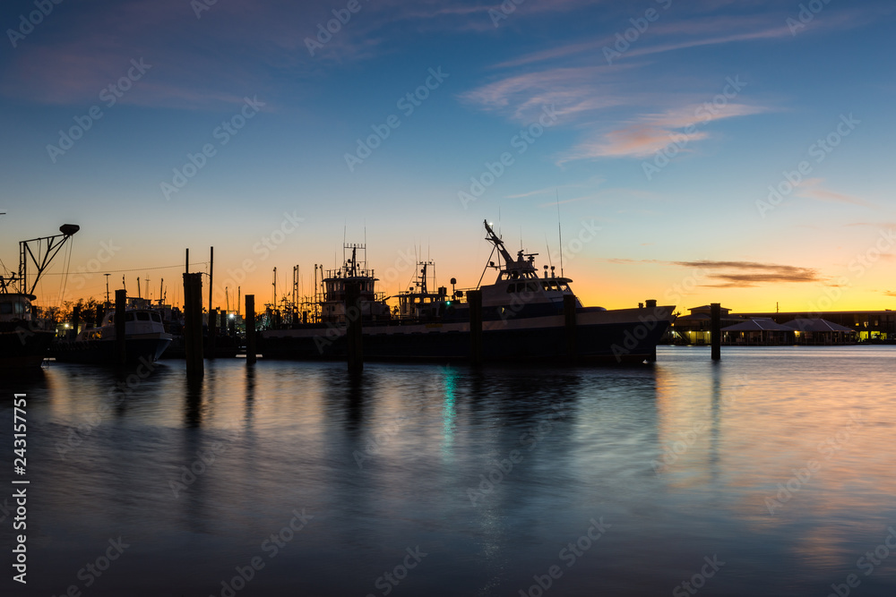 Sunset behind a silhouette of a resting shrimp boat with calm water