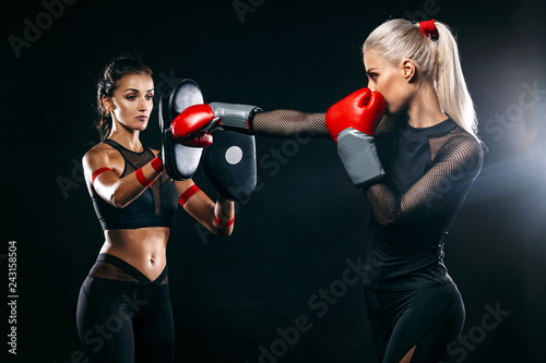 Two women athlete and boxer trainging before fight on black background. Sport and boxing concept.