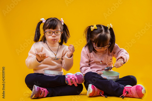 Dark-haired unusual children with chromosome abnormality eating breakfast