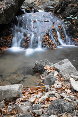 fall scenery in forest with flowing river waterfall in long exposure in selective colors