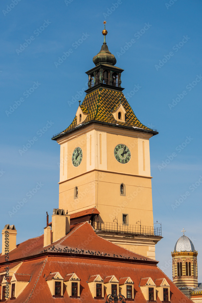 Tower clock of the Council House building in Brasov, Transylvania on a blue sky background, situated in the historic Council Square - Piata Sfatului. Baroque architecture landmark.