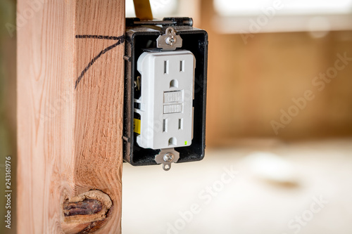 Φωτογραφία White plastic electrical outlet mounted in a box and a wood stud