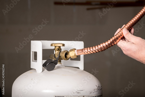 Man tries to fit a copper pipe onto a propane bottle photo