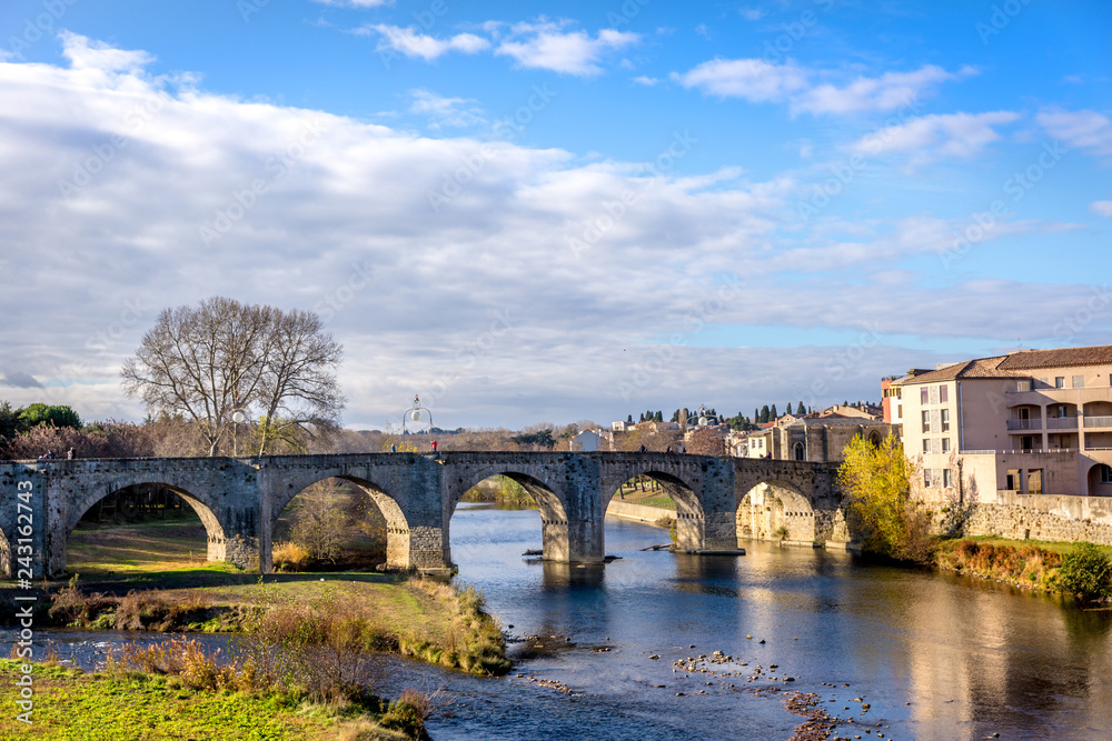 An old bridge crossing a calm river in Carcassonne in France in a blue sky day