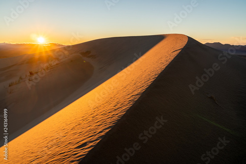 Wind carved ridge in a sand dune with the setting sun in the bcakground  Kelso Sand Dunes  Mojave National Preserve  California