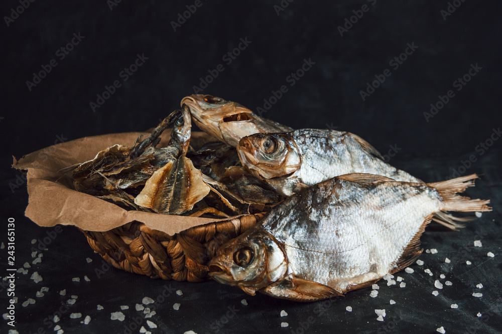 Basket of dried fish in craft paper on a dark background