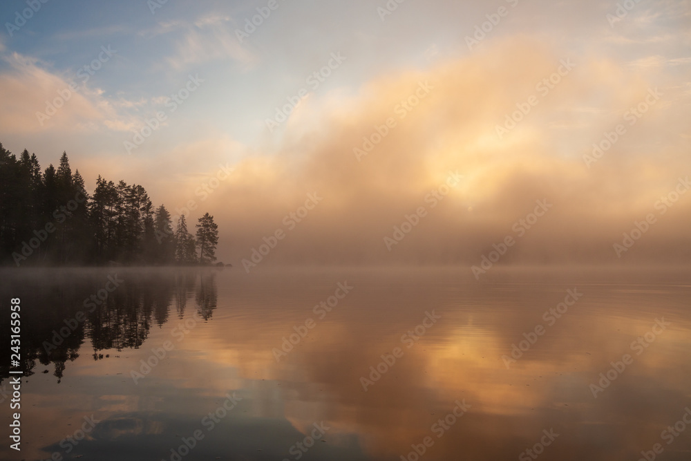 Fog rising from lake at summer morning sunrise landscape