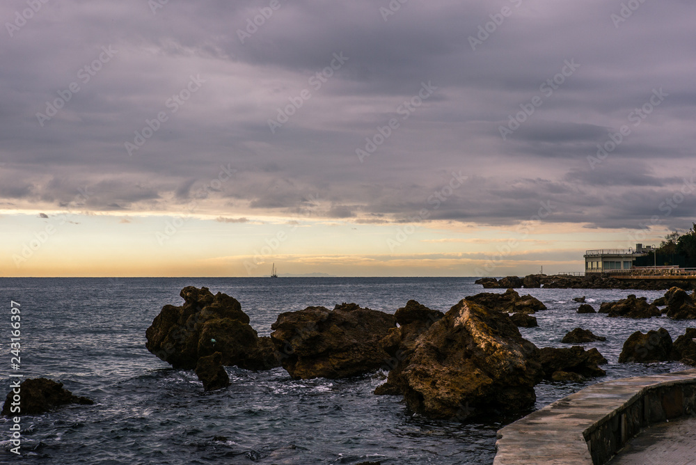 The promenade of Castiglioncello in Tuscany in winter at sunset with a island and a sailing boat on the horizon - 3
