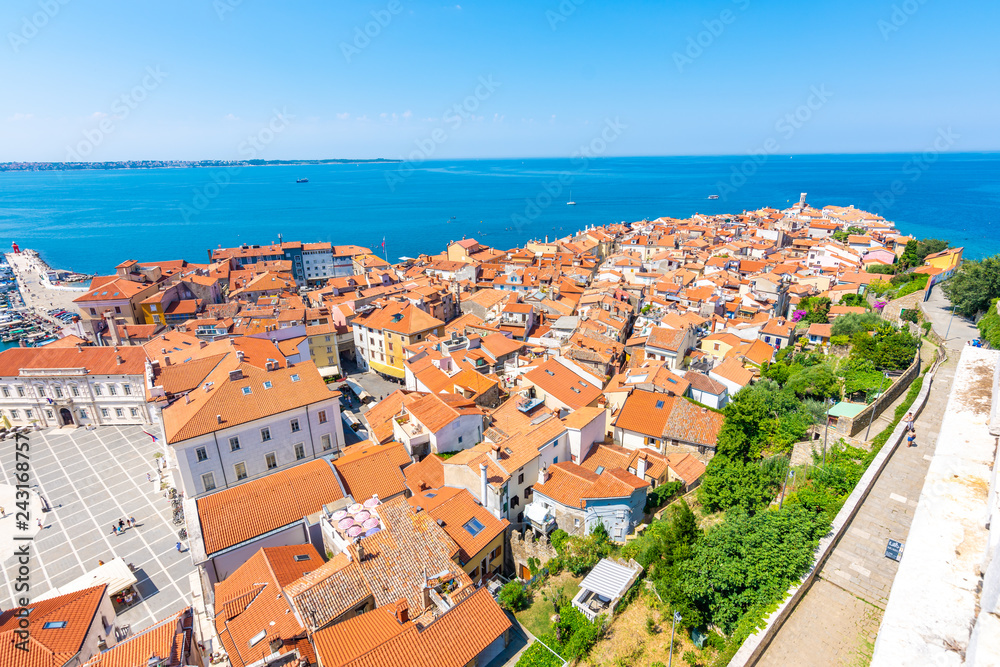Aerial panorama view of Piran city, Slovenia. Look from tower in church. In foreground are small houses, Adriatic sea in background. Summer weather in famous tourist destination