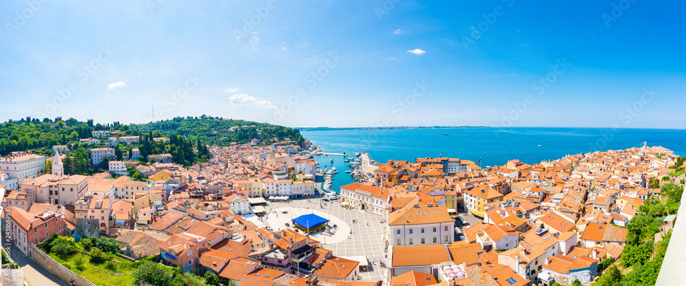 Aerial panorama view of Piran city, Slovenia. Look from tower in church. In foreground are small houses, Adriatic sea in background. Summer weather in famous tourist destination