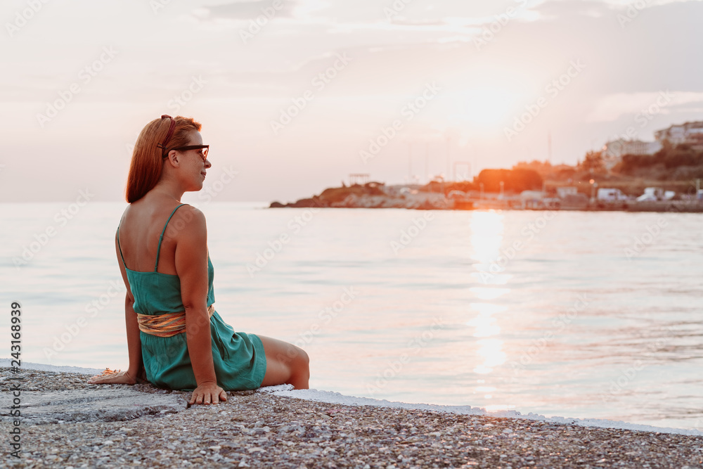 Young woman enjoying sunset by the sea