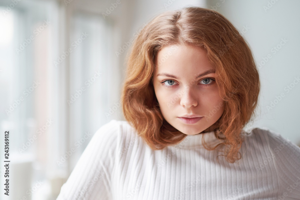 Close up portrait of young beautiful girl . Day light from window, white room as background. red curly hair Close up portrait of young beautiful girl . Day light from window, white room as background. red curly hair