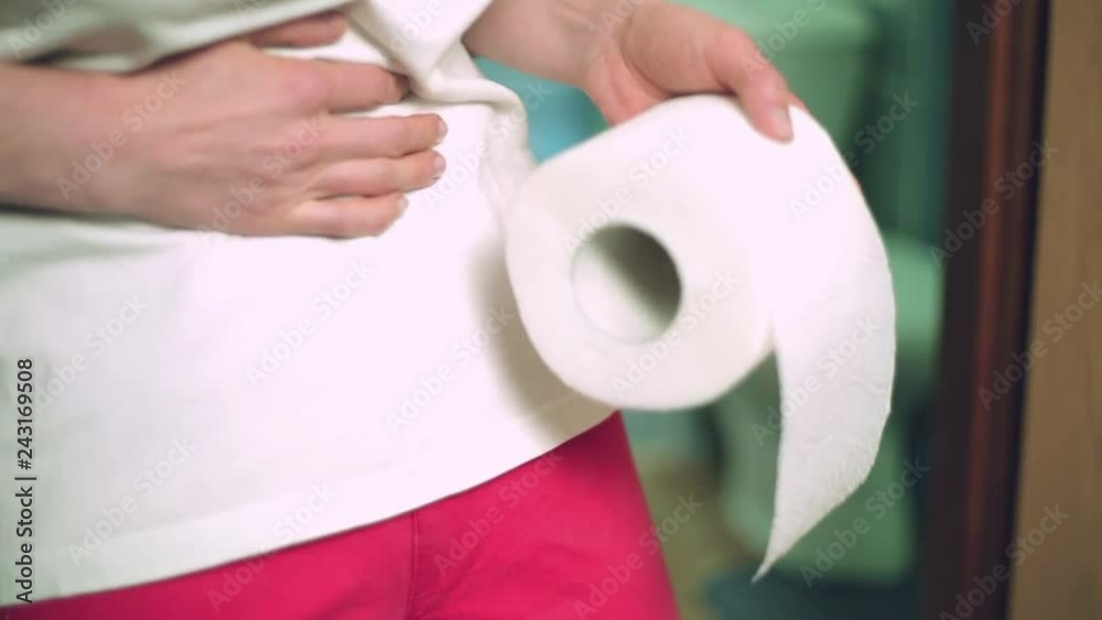 A woman with toilet paper holds on to a sore stomach, goes to the