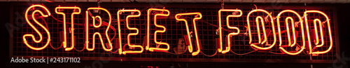 Street Food Neon sign on a Graffiti. Bricks wall