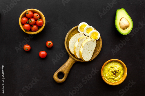 Healthy breakfast. Toasts with vegetables and guacamole on black background top view
