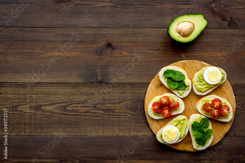 Healthy snacks. Set of toasts with vegetables like avocado, guacamole, rocket, cherry tomatoes on dark wooden background top view copy space