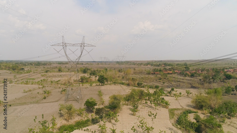 Electricity pylons bearing power supply across rural landscape. aerial view power pylons and high voltage lines java, indonesia.High voltage metal post, tower. Electric Power Transmission Lines over