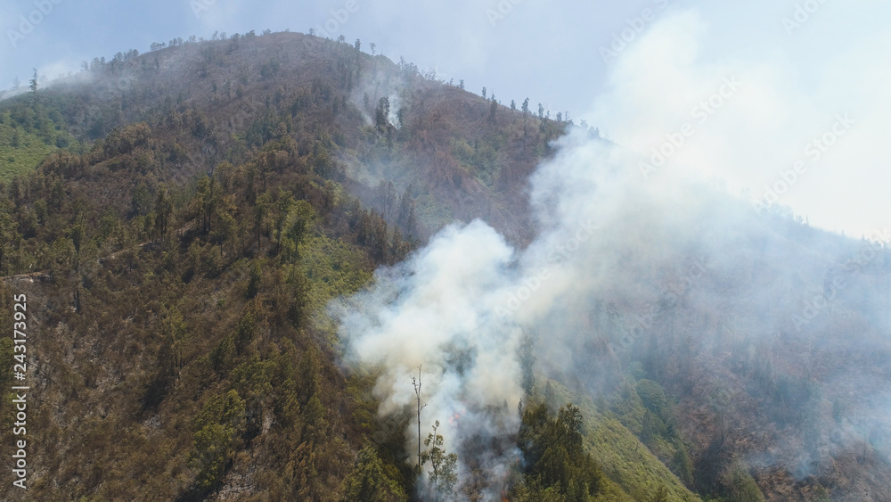 aerial view forest fire smoke on slopes hills. wild fire in tropical forest, Java Indonesia. natural disaster fire in Southeast Asia