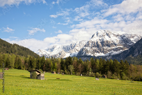 View of the village of Ehrwald (Austria) and its beautiful surrounding mountains (Zugspitze Arena) and green alp meadows. Shot in afternoon sunlight.